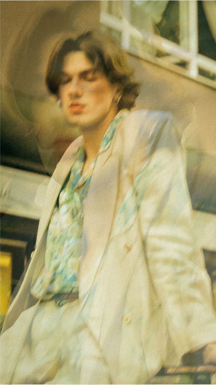 A creative double exposure image of a stylish man in a white suit blending with an abstract background.